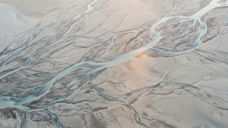Pale, braided river channels spreading across a wide plain, seen from directly above.