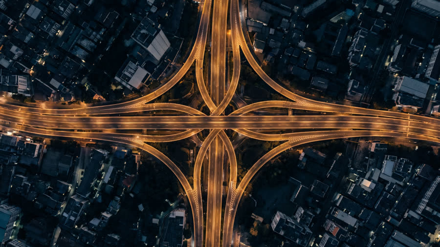A large motorway interchange lit up at night, seen from directly above.